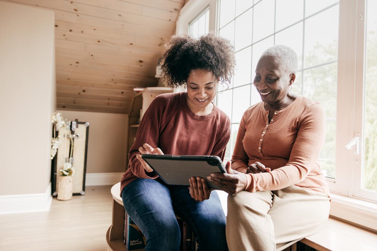 Two women sitting next to each other looking at a tablet