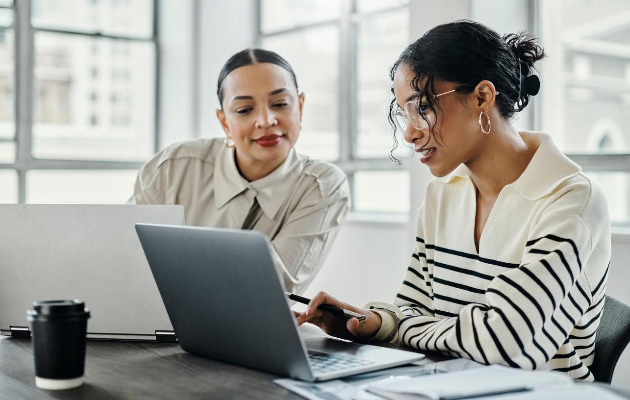 Two business women sitting at a table and working on their laptops