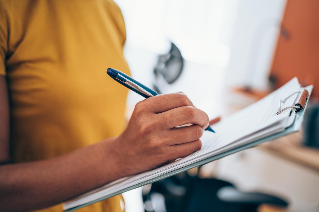 Businesswoman making notes on a clipboard inside of the office.