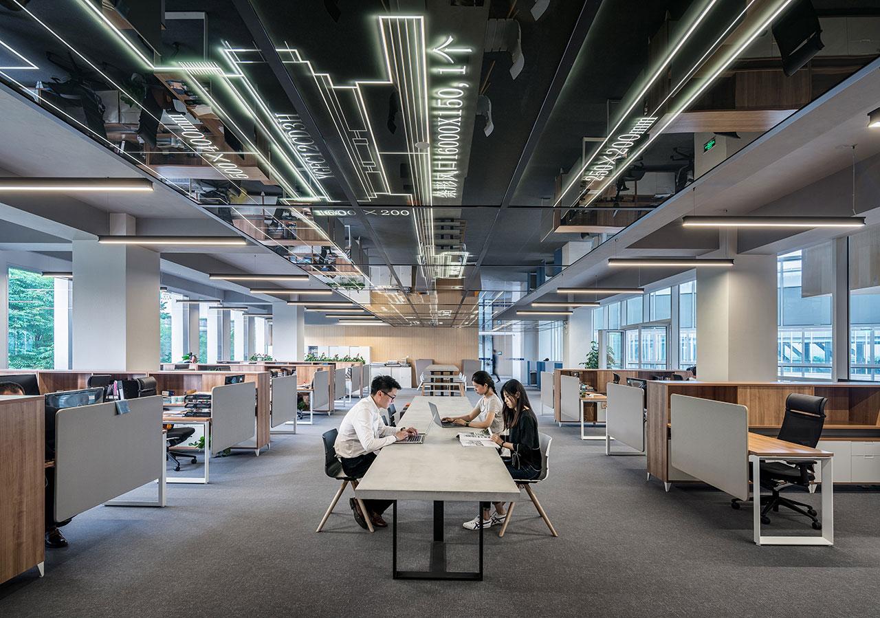 Three business people sitting in a large room while typing