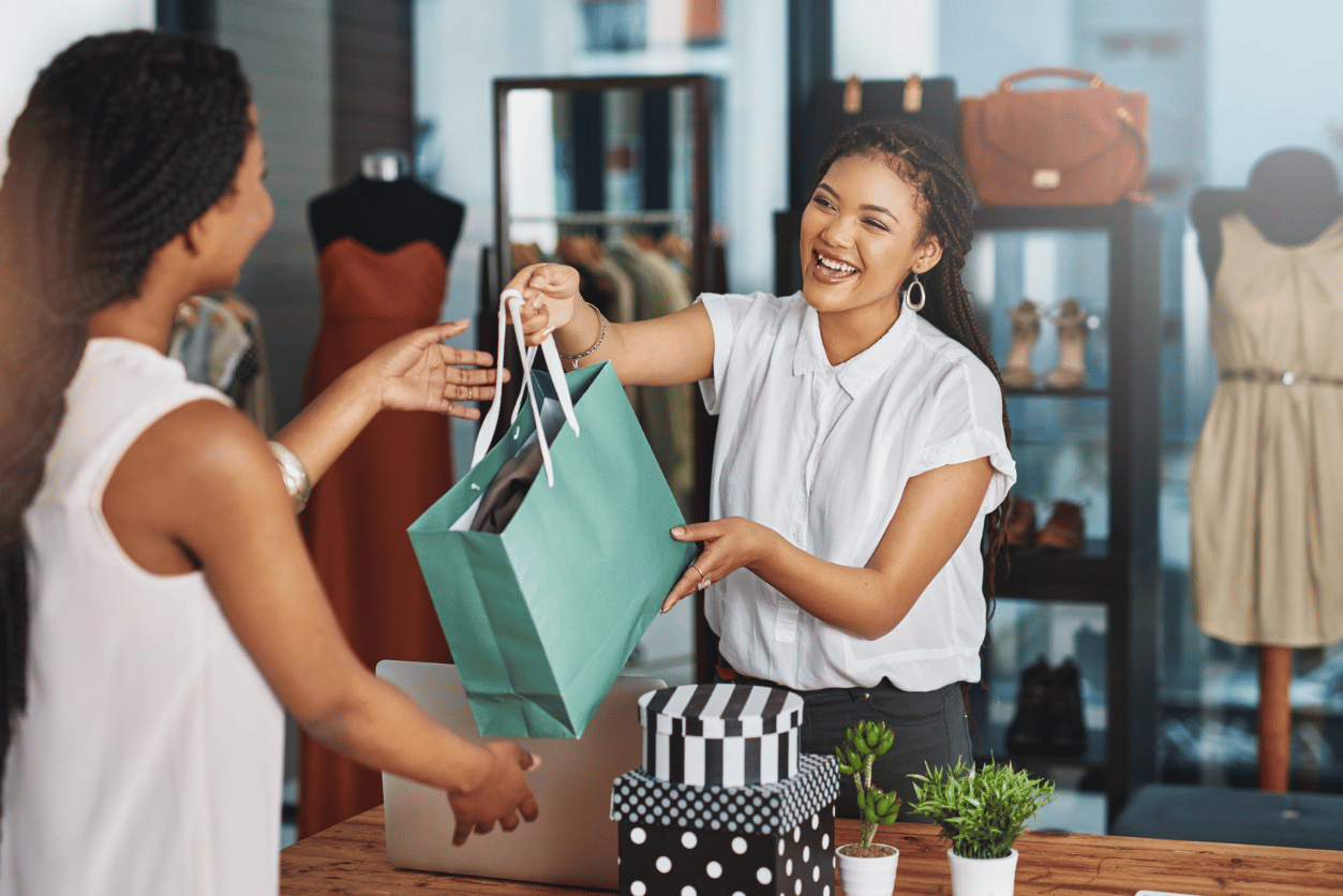 Primark + Pearl-Plaza customer story - image of a woman behind a shopping counter handing another woman a shopping bag