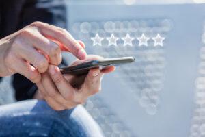 Close-up of Woman's Hand Holding a Smart Phone with Icon Five Star Symbol